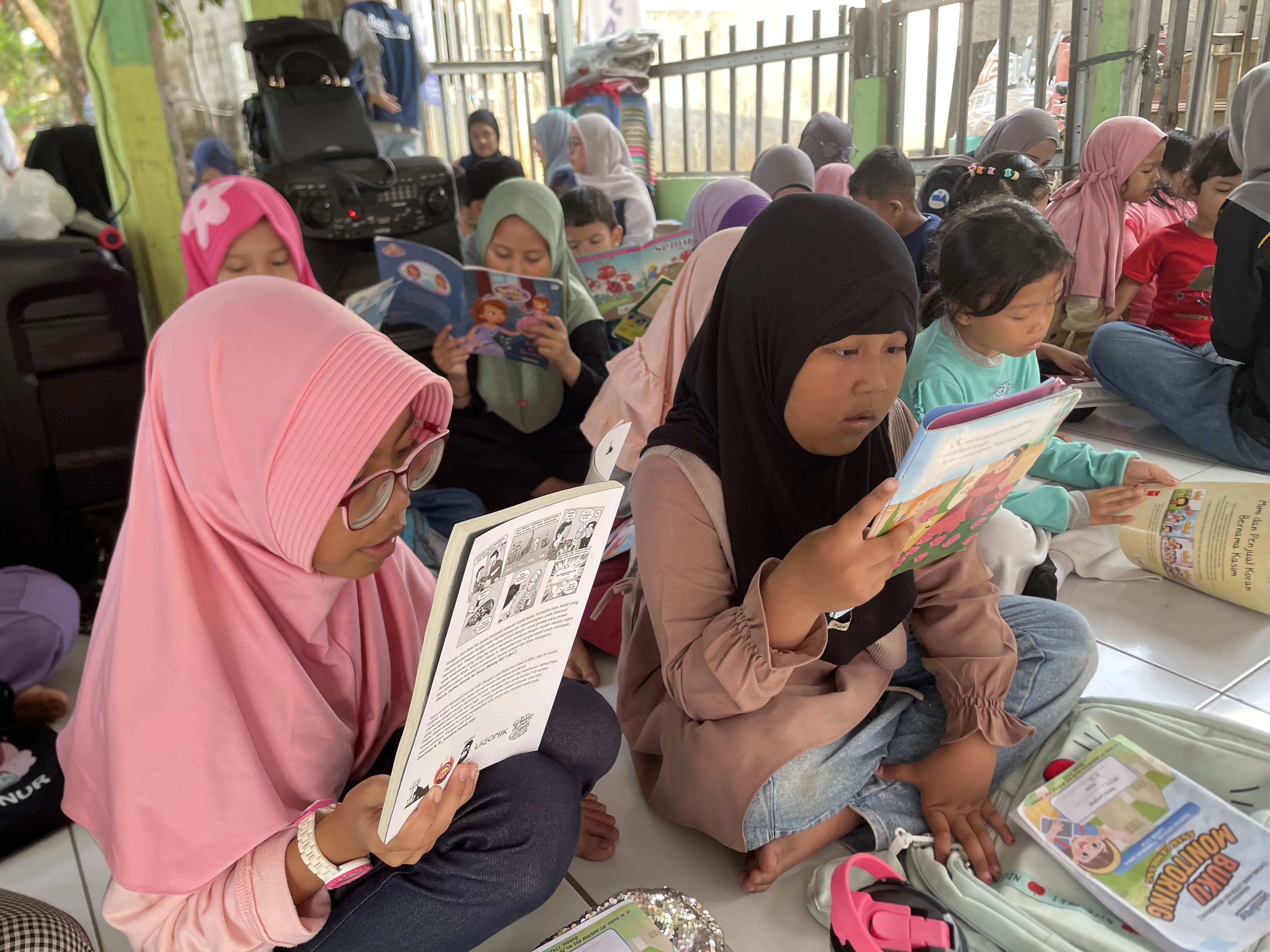 Relawan membacakan buku untuk anak di atas tikar