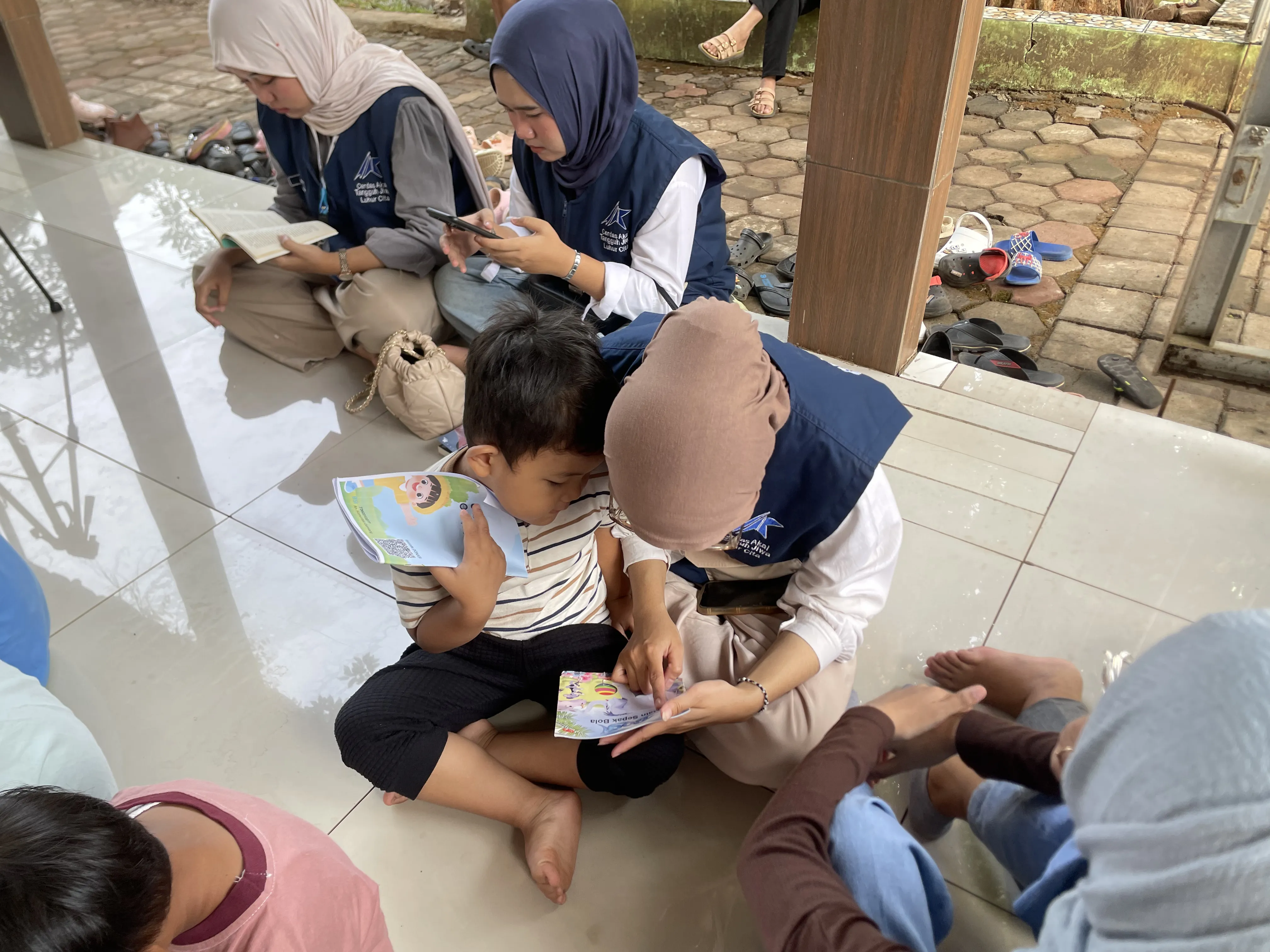 Relawan mendampingi anak membaca di meja kecil